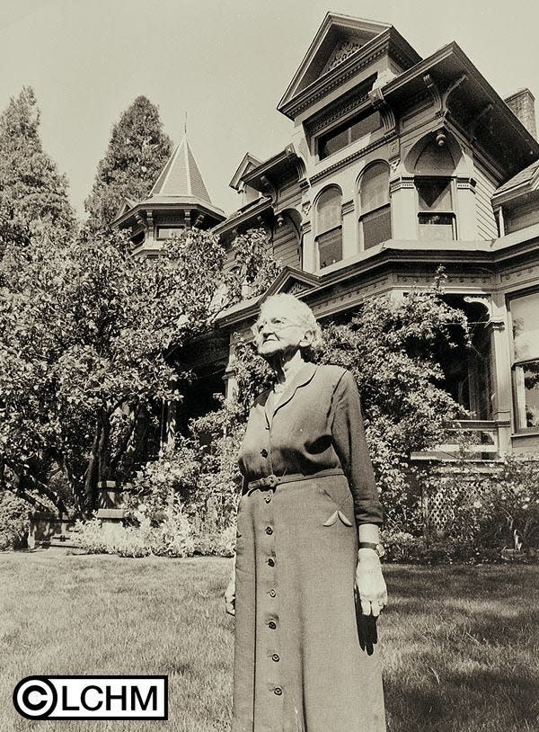 Shelton-McMurphey-Johnson house at 303 Willamette Street in Eugene. Built 1888. Exterior view from SE with owner Eva Frazer Johnson in foreground; photo taken ca. 1968. Photographer unknown.