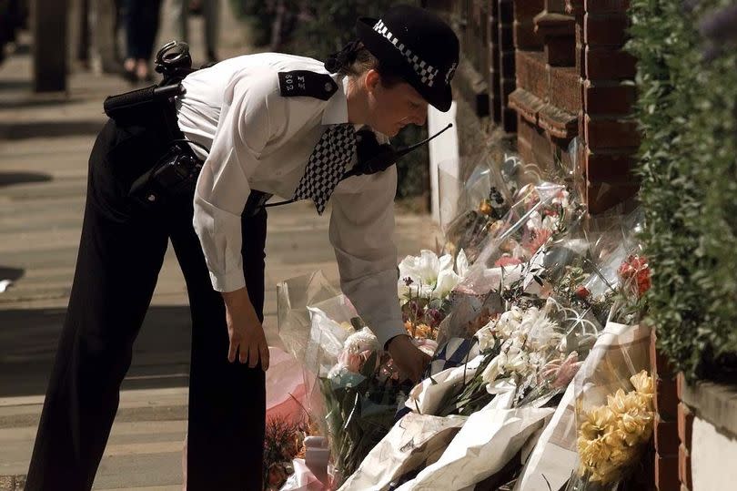 A police officer lays flowers outside Jill Dando's house, in Gowan Avenue, Fulham, in April 1999 after she had been murdered