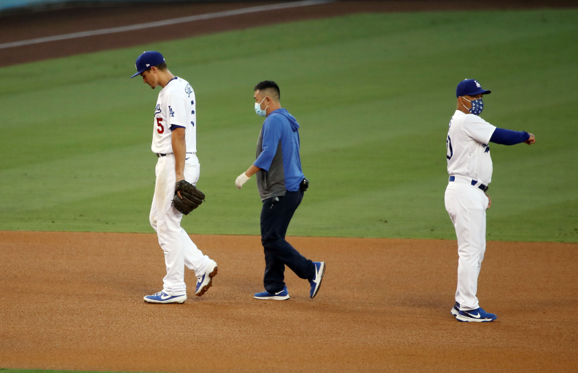 Dodgers shortstop Corey Seager walks off the field with a team trainer.