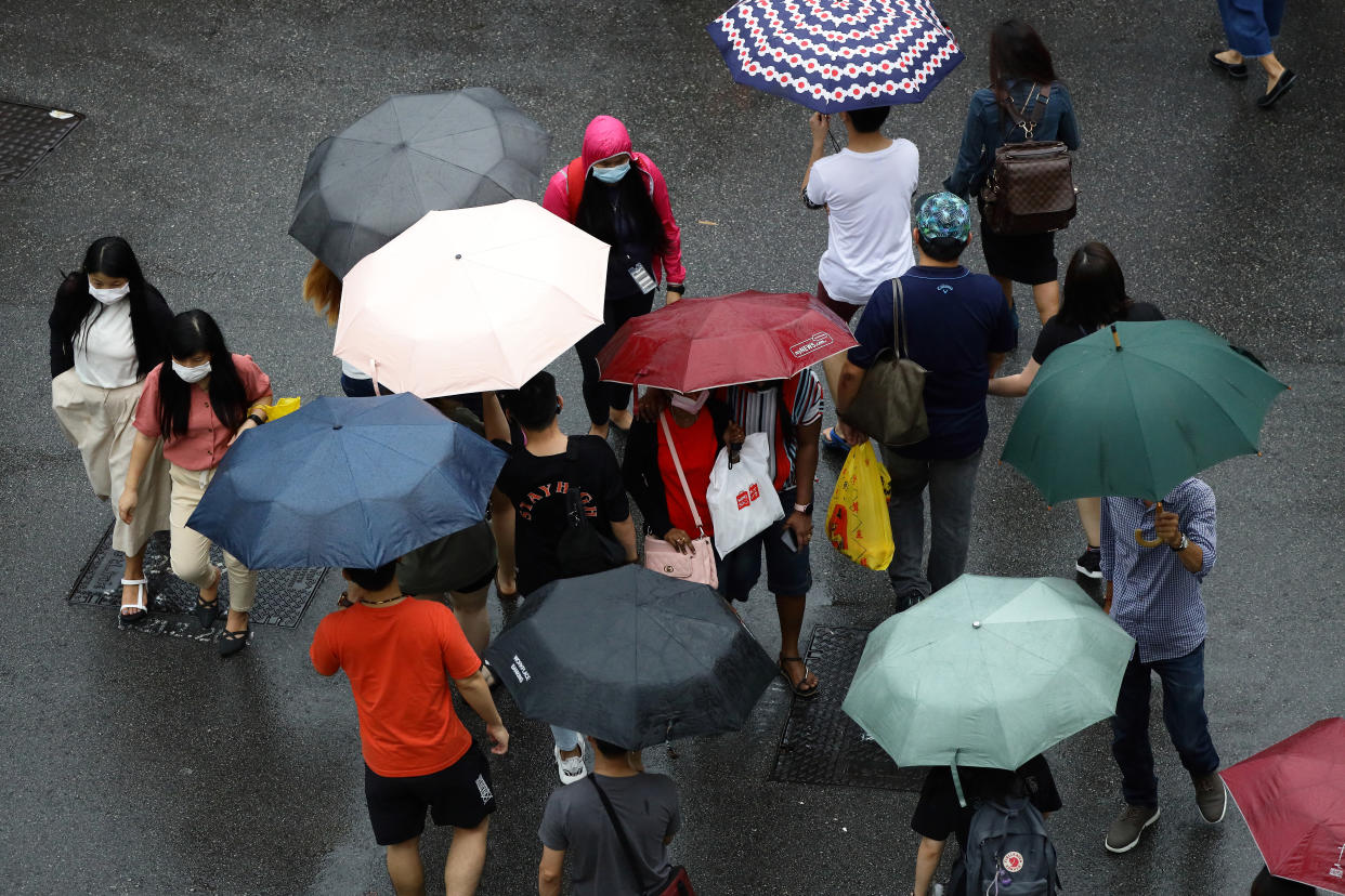 Pedestrians crossing a street in the rain in Singapore.