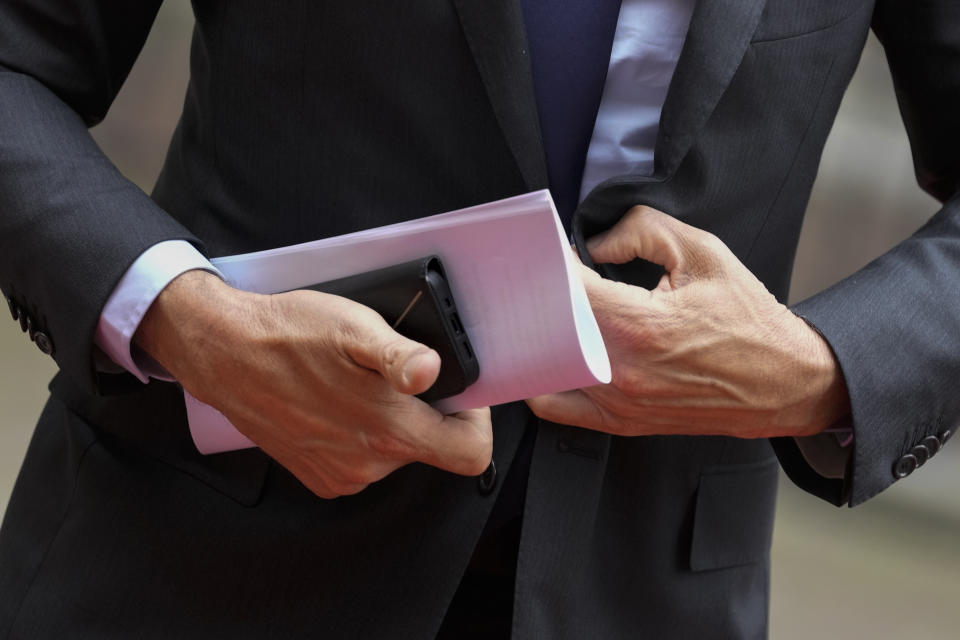 Dutch Prime Minister Mark Rutte holds his smartphone as he gets out of his car prior to the arrival of German Chancellor Olaf Scholz in The Hague, Netherlands, Thursday, May 19, 2022. (AP Photo/Peter Dejong)