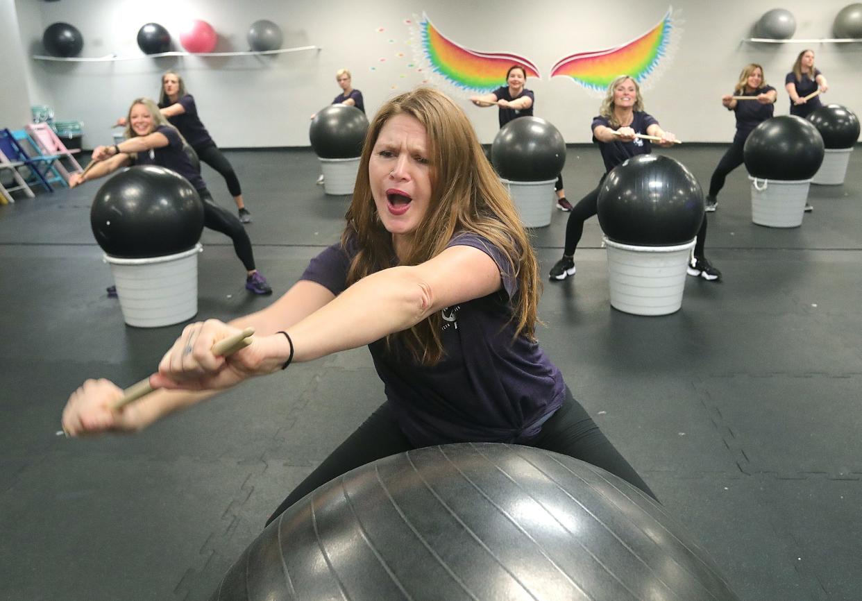 Tyrannosaurus Flex Fitness owner Kellie Dziemianzuk leads a cardio drum demonstration with her staff Thursday in Stow.