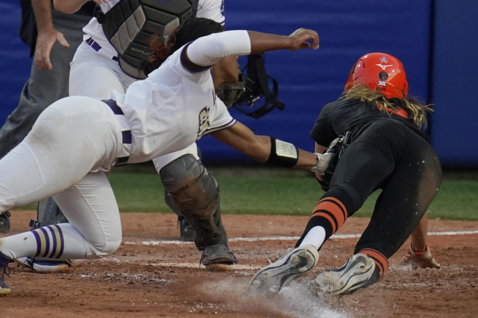 Oklahoma State's Scotland David, right, is tagged out at home plate by James Madison pitcher Odicci Alexander, left, in the seventh inning of a Women's College World Series softball game, Friday, June 4, 2021, in Oklahoma City. (AP Photo/Sue Ogrocki)