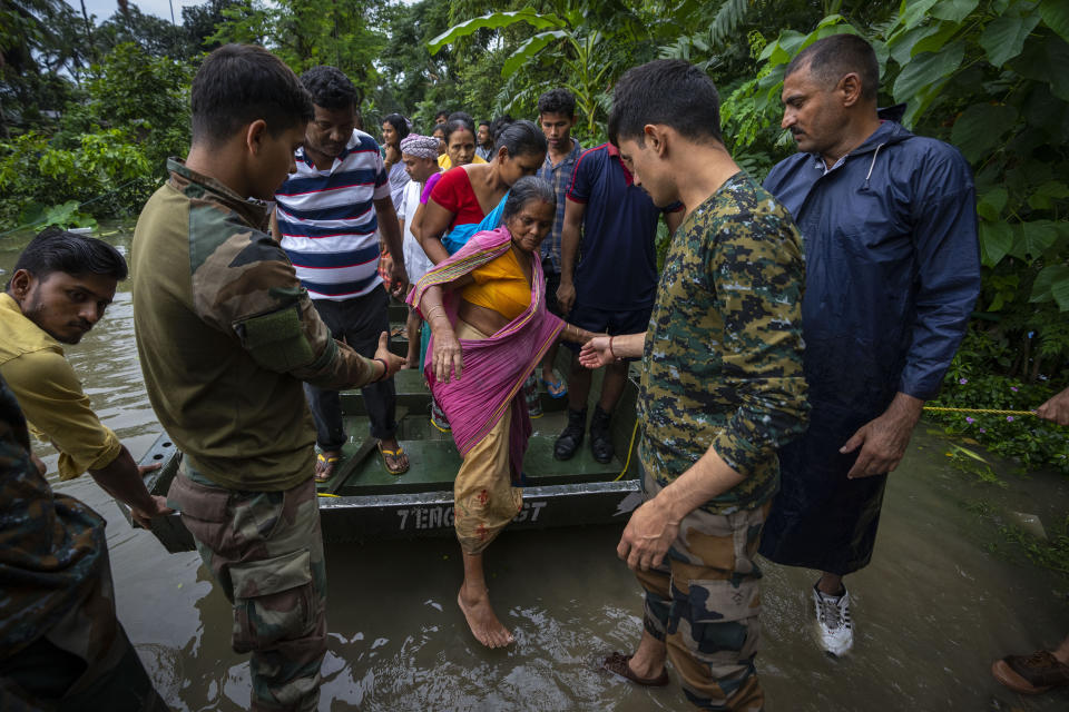 Indian army personnel rescue flood-affected villagers on a boat in Jalimura village, west of Gauhati, India, Saturday, June 18, 2022. More than a dozen people have died as massive floods ravaged northeastern India and Bangladesh, leaving millions of homes underwater and severing transport links, authorities said Saturday. (AP Photo/Anupam Nath)