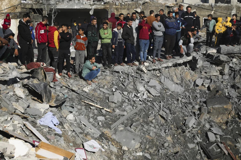 Palestinians watch the destruction after the Israeli bombardment of the Gaza Strip outside a morgue in Rafah, Tuesday, Dec. 19, 2023. (AP Photo/Hatem Ali)