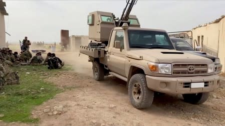 Still image from video shows a military vehicle driving past Syrian rebel fighters near Tal Abyad