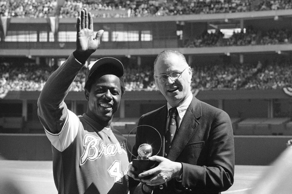 FILE - Atlanta Braves' Hank Aaron waves to the crowd as baseball commissioner Bowie Kuhn presents him with a trophy in Cincinnati after Aaron tied Babe Ruth's all-time home run mark, in this April 4, 1974, file photo. Aaron died Jan. 22, 2021. Kuhn was commissioner from Feb. 4, 1969 to Sept. 30, 1984. (AP Photo/Bob Johnson, File)