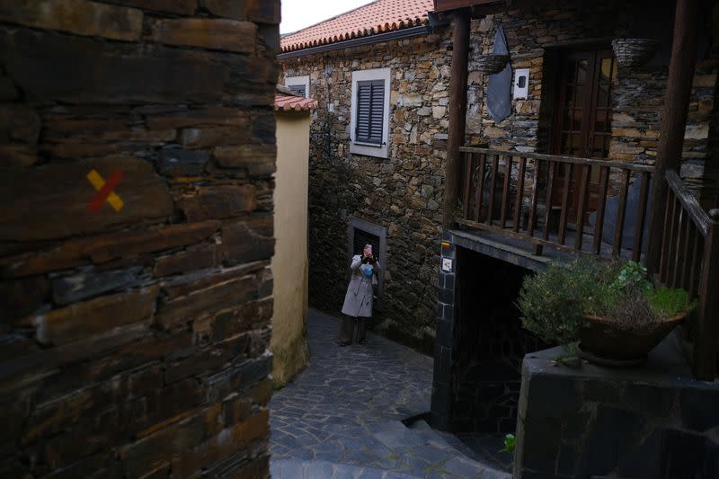 A woman takes a photo in the schist village of Fajao, Pampilhosa da Serra