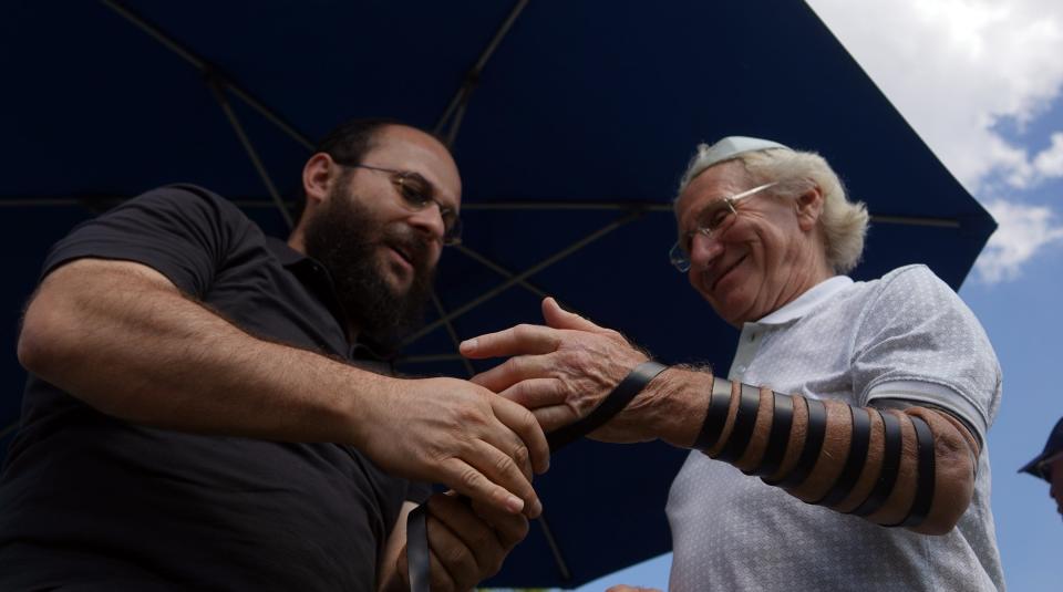 Rabbi Leib Ezagui wraps Ian Nissim's arm during a gathering of about 200 people during a pro-Israel rally at The Great Lawn of West Palm Beach in October.