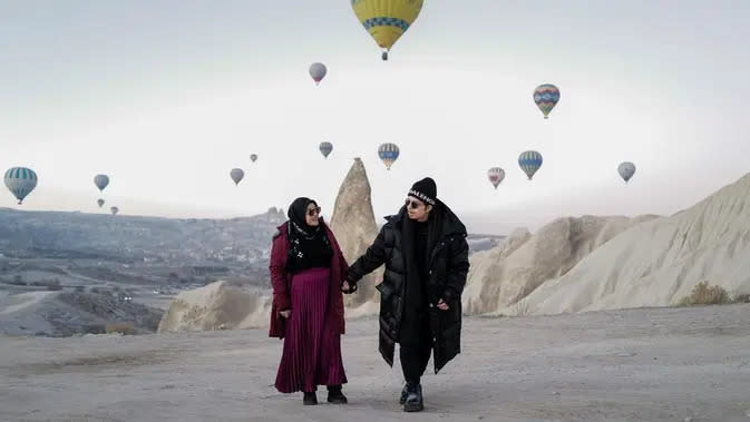 Pasangan yang menikah pada April 2021 silam itu tampak berpose di antara banyak balon-balon udara di belakangnya. Salah satu yang paling populer di Cappadocia adalah wisata balon udara. (Instagram/aurelie.hermansyah)