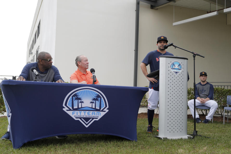 José Altuve (al micrófono) pide disculpas en nombre del equipo por el robo de señales que hicieron los Astros en las temporadas del 2017 y 2018. Lo observan el propietario del equipo Jim Crane (sentado, a la derecha) y el nuevo mánager Dusty Baker. Foto del 13 de febrero del 2020 en el campamento de pretemporada de los Astros en West Palm Beach, Florida. (AP Photo/Jeff Roberson).