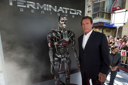 Cast member Arnold Schwarzenegger poses by a Terminator replica at the premiere of "Terminator Genisys" in Hollywood, California June 28, 2015. The movie opens in the U.S. on July 1. REUTERS/Mario Anzuoni