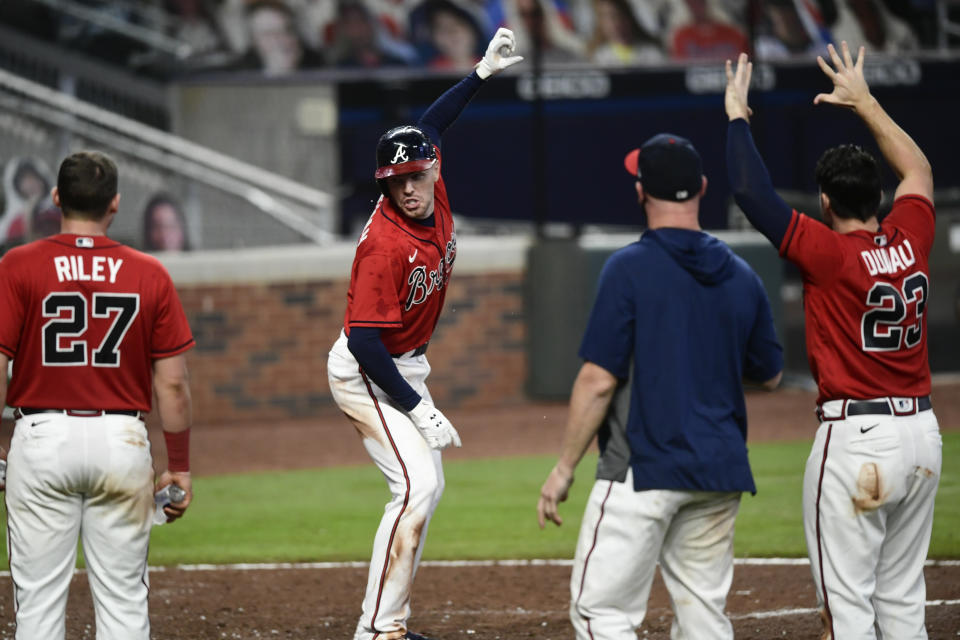 Atlanta Braves' Freddie Freeman, center, pretends to take a selfie at home plate as he and others celebrate his winning two-run home during the eleventh inning of a baseball game against the Boston Red Sox, Friday, Sept. 25, 2020, in Atlanta. (AP Photo/John Amis)