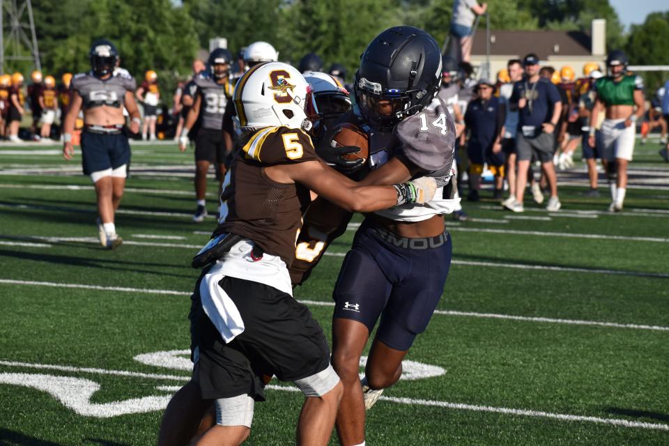 Decatur Central's Desmond Coleman gets wrapped up by Speedway defenders after hauling in a pass during the Hawks' four-way scrimmage with the Sparkplugs, Bloomington North and Castle on June 23, 2022.