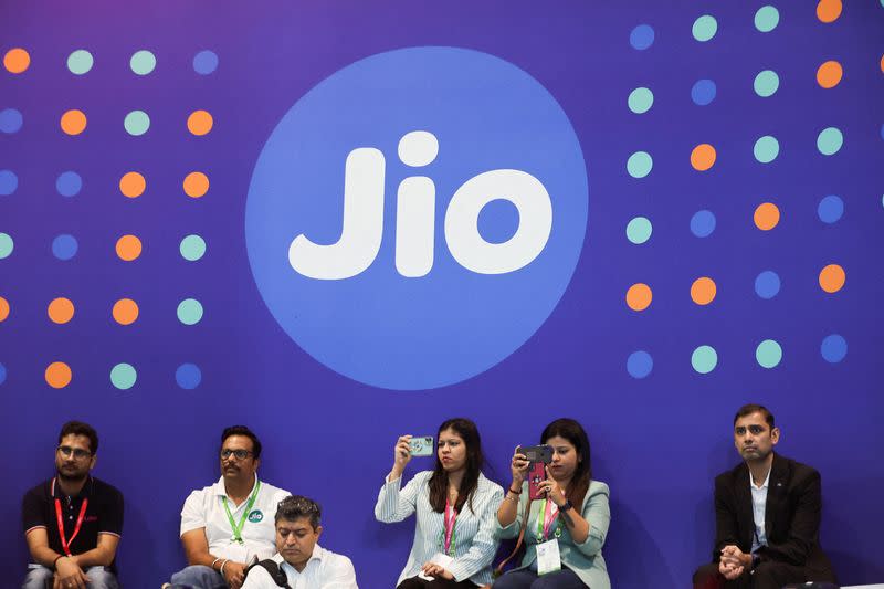 FILE PHOTO: People take pictures with their mobile phones in front of a board with the logo of Jio at the ongoing India Mobile Congress 2022, at Pragati Maidan, in New Delhi