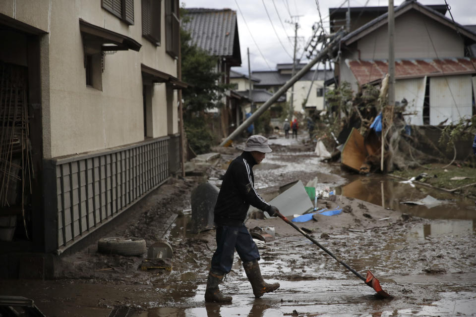 A man cleans up mud in a neighborhood destroyed by Typhoon Hagibis Tuesday, Oct. 15, 2019, in Nagano, Japan. More victims and damage have been found in typhoon-hit areas of central and northern Japan, where rescue crews are searching for people still missing. (AP Photo/Jae C. Hong)