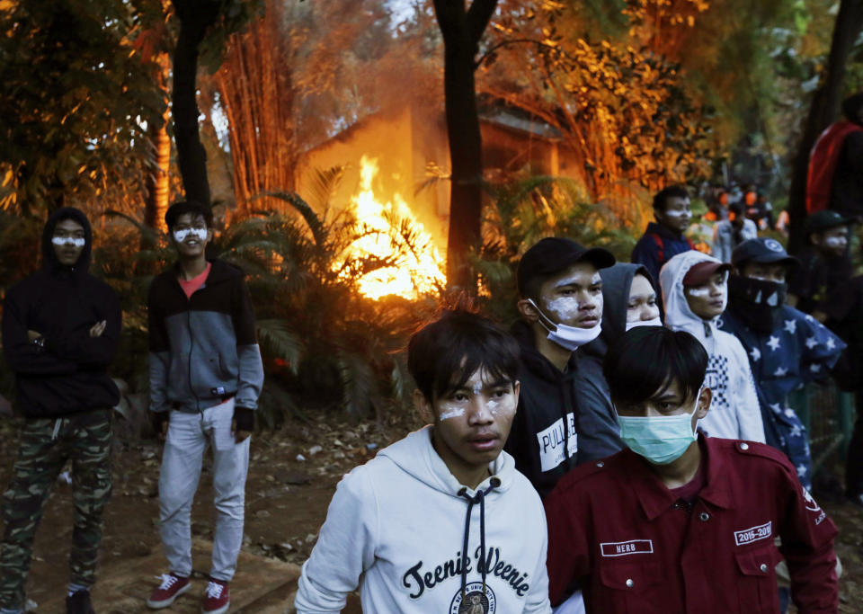 Protesters with toothpaste smeared around their eyes to evade the effect of tear gas, stand near burning debris during a clash with riot police in Jakarta, Indonesia, Monday, Sept. 30, 2019. Thousands of Indonesian students resumed protests on Monday against a new law they say has crippled the country's anti-corruption agency, with some clashing with police. (AP Photo/Dita Alangkara)