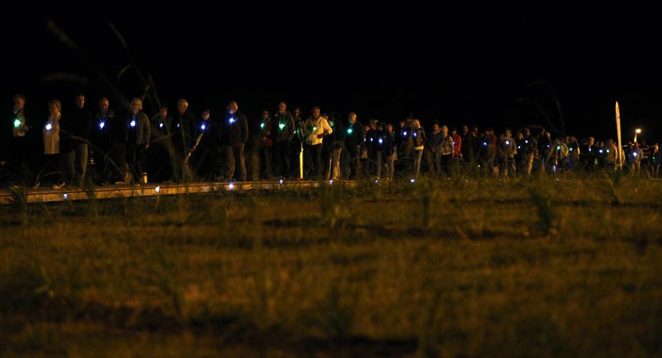 People walk on a boardwalk during "Marche Silencieuse de la Lumiere et de la Vie" in Lac-Megantic