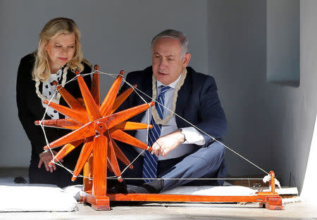 Israeli Prime Minister Benjamin Netanyahu spins cotton on a wheel as his wife Sara looks on during their visit to Gandhi Ashram in Ahmedabad, India, January 17, 2018. REUTERS/Amit Dave