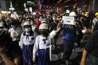 Pro-democracy protesters flashing three fingers as they march to the German Embassy in central Bangkok, Thailand, Monday, Oct. 26, 2020. As lawmakers debated in a special session in Parliament that was called to address political tensions, student-led rallies were set to continue with a march through central Bangkok on Monday evening to the German Embassy, apparently to bring attention to the time King Maha Vajiralongkorn spends in Germany. The sign translated reads, "People see you in Germany." (AP Photo/Gemunu Amarasinghe)