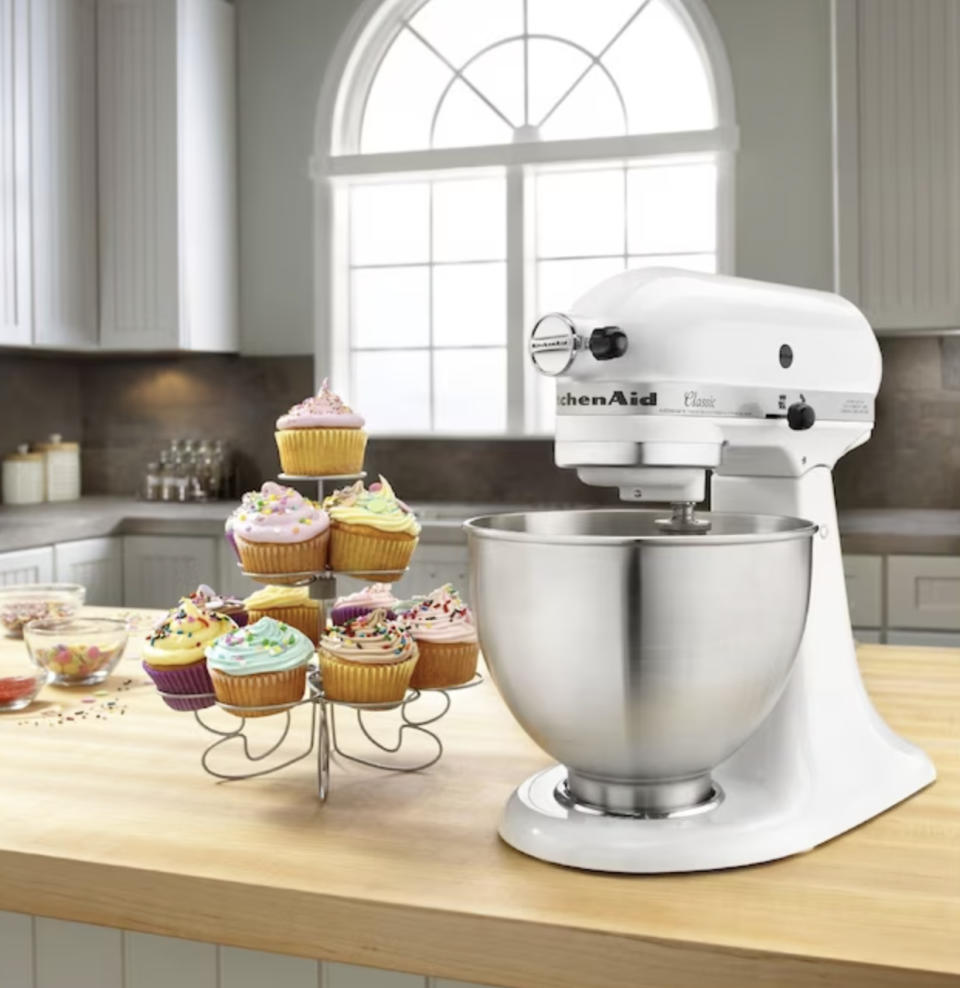 the white stand mixer on counter next to tower of cupcakes
