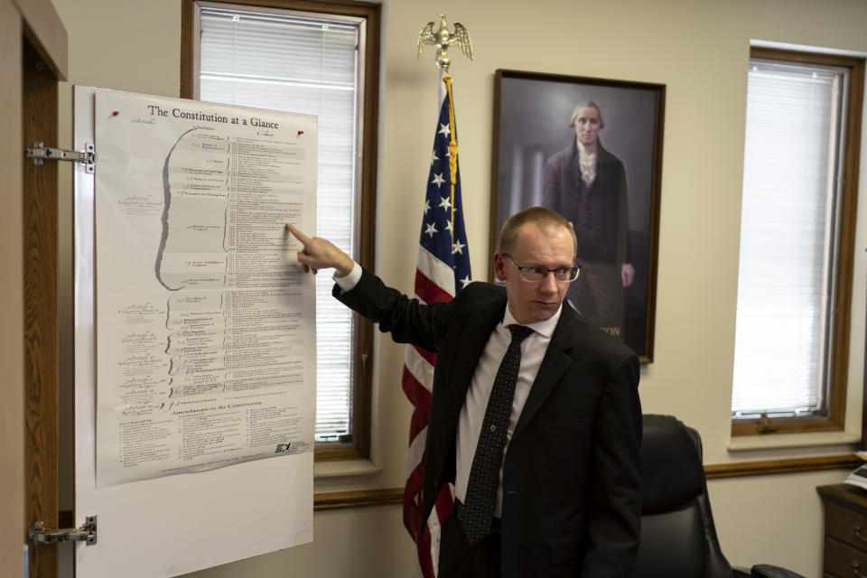 CEO Bill Hahn points to articles of the Constitution in his office during an interview at the headquarters of the John Birch Society in Appleton, Wis., Thursday, Nov. 17, 2022. (AP Photo/David Goldman)
