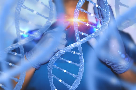 Enlarged image of DNA helixes in front of physician pointing to a section of the DNA with light appearing where he's pointing