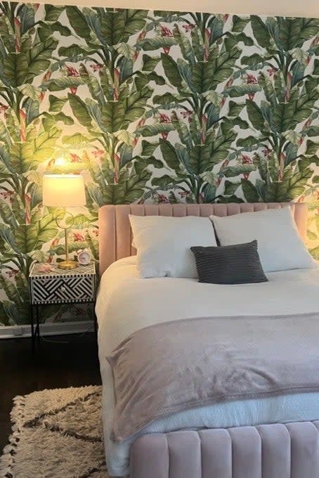 a reviewer photo of the banana leaf wallpaper in a bedroom