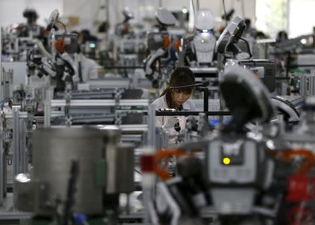 A humanoid robot works side by side with employees in the assembly line at a factory of Glory Ltd., a manufacturer of automatic change dispensers, in Kazo, north of Tokyo, Japan, July 1, 2015. REUTERS/Issei Kato