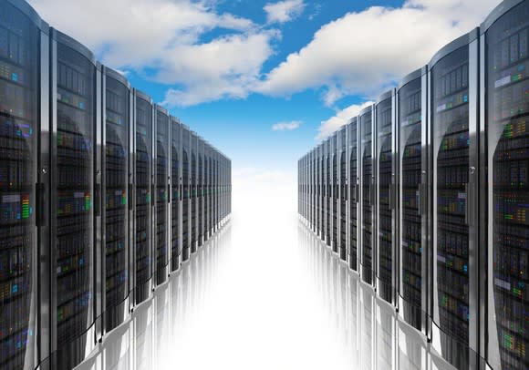 Rows of server racks, as in a modern data center, but under a blue sky with fluffy white clouds.