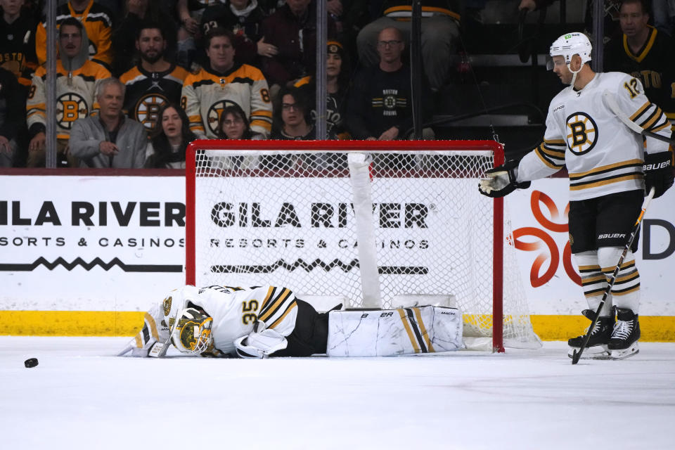 An injured Boston Bruins goaltender Linus Ullmark (35) pauses on the ice as defenseman Kevin Shattenkirk (12) skates in to check on Ullmark during overtime an NHL hockey game against the Arizona Coyotes onTuesday, Jan. 9, 2024, in Tempe, Ariz. The Coyotes won 4-3. (AP Photo/Ross D. Franklin)