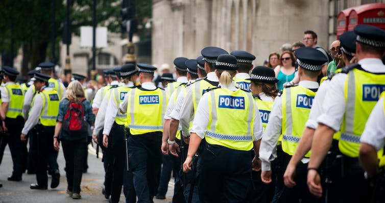 View from behind of a large group of male and female police officers walking on a public street