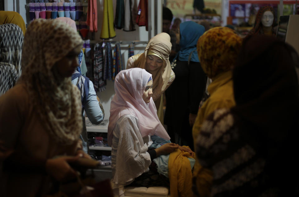 In this Thursday, May 30, 2013 photo, an Indonesian Muslim woman tries on a headscarf during Islamic Fashion Fair in Jakarta, Indonesia. Indonesia is the world's most populous Muslim country, but most people follow a moderate form of the religion. Many women wear bright and creative headscarves along with brand-name jeans and long-sleeved fitted shirts. (AP Photo/Dita Alangkara)