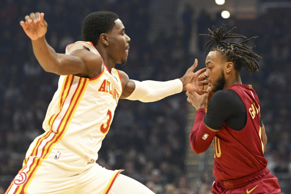 Cleveland Cavaliers guard Darius Garland, right, is fouled by Atlanta Hawks guard Aaron Holiday, left, during the first half of an NBA basketball game, Monday, Nov. 21, 2022, in Cleveland. (AP Photo/Nick Cammett)