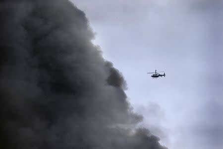 A New York City Police helicopter flies near billowing smoke above the site of a residential apartment building collapse and fire in New York City's East Village neighborhood, March 26, 2015. REUTERS/Brendan McDermid