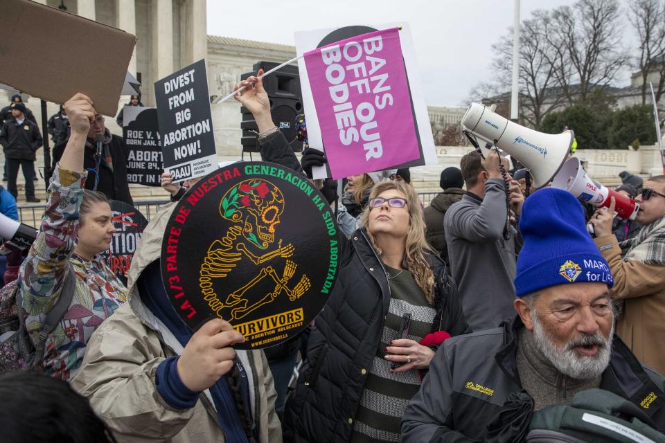 An abortion rights demonstrator blocks out an anti-abortion sign during the Women's March, which largely focused on abortion rights, in front of the Supreme Court in Washington, Sunday, Jan. 22, 2023. (AP Photo/Amanda Andrade-Rhoades)