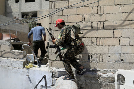 A member of the Syrian Democratic Forces moves from house to house to hide from Islamic State's sniper in the old city of Raqqa. REUTERS/Zohra Bensemra