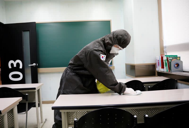 A South Korean worker cleans a desk with disinfectant at a cram school teaching math, amid the rise in confirmed cases of coronavirus disease (COVID-19) in Daegu