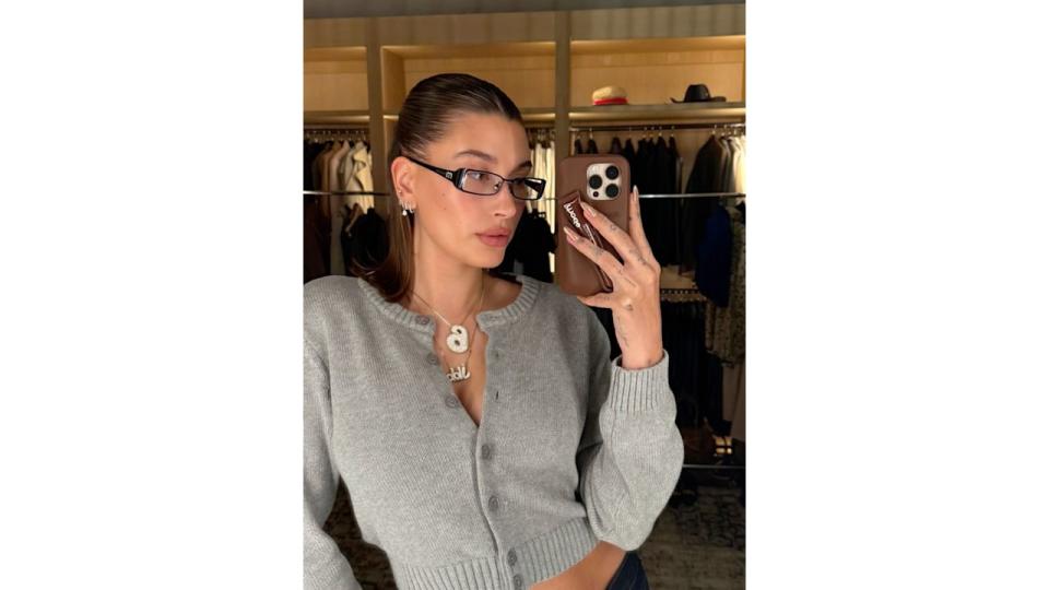 Hailey Bieber poses for a mirror selfie on her instagram story in a grey knit cardigan and a pair of slim glasses