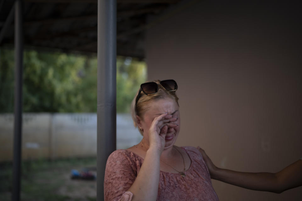 Natalia Rosolova cries outside her home in Kupiansk-Vuzlovyi, Ukraine, Wednesday, Aug. 23, 2023. Residents of the war-ravaged settlement close to the northeast frontline are ignoring calls from Ukrainian authorities to evacuate as the fighting inches closer. (AP Photo/Bram Janssen)