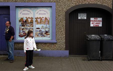 People stand next to an empty shop which has been covered with artwork to make it look more appealing, in the village of Bushmills on the Causeway Coast August 20, 2013. REUTERS/Cathal McNaughton