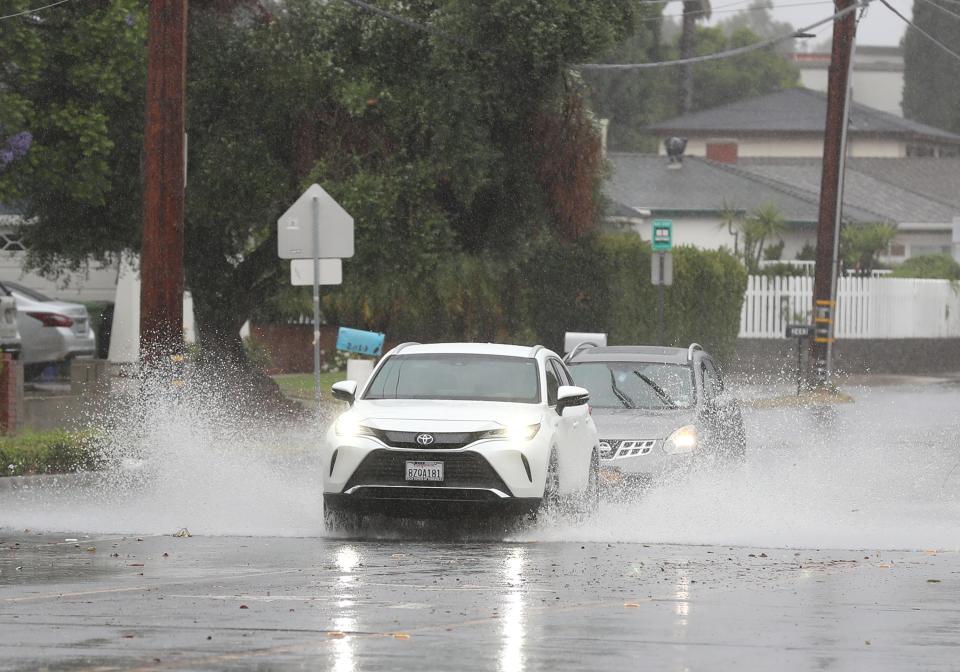 Cars negotiate a flooded intersection at Cochran and Heather streets in Simi Valley on Sunday.