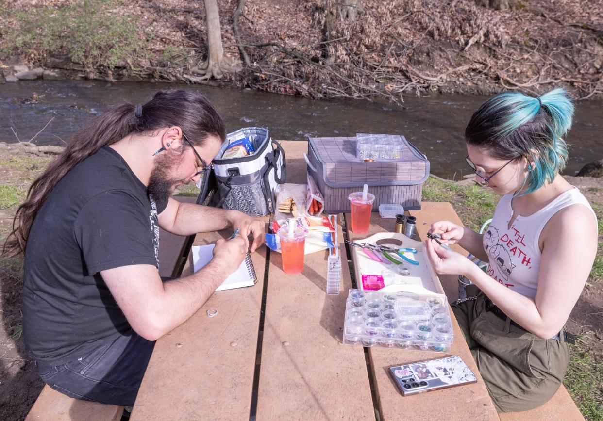 Kaia Nolan makes jewelry while Nathan Talafous draws Monday, April 8, 2024, while spending some time in the sun at Massillon's Reservoir Park.