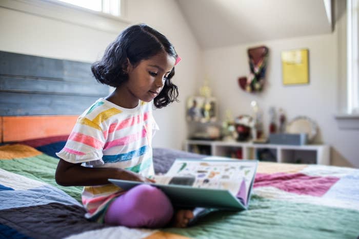 a child reading a book on her bed