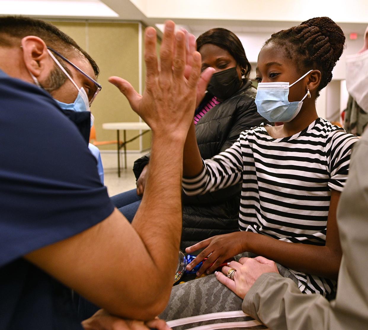 Paisley Twum, 11, high-fives Dr. Dahod Idris after Twum received a COVID-19 vaccine at the Boys & Girls Club of Worcester.