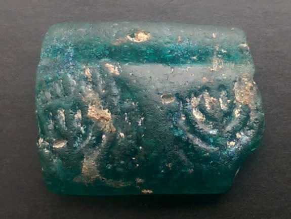 This glass fragment, embossed with two menorahs, was discovered by archaeologists in Israel on the second night of Hanukkah.