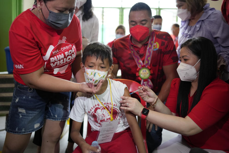 A boy receives a COVID-19 Pfizer vaccine during the opening of classes at the San Juan Elementary School in metro Manila, Philippines on Monday, Aug. 22, 2022. Millions of students wearing face masks streamed back to grade and high schools across the Philippines Monday in their first in-person classes after two years of coronavirus lockdowns that are feared to have worsened one of the world's most alarming illiteracy rates among children. (AP Photo/Aaron Favila)