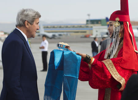 A woman in traditional attire presents U.S. Secretary of State John Kerry with cheese curds as he disembarks from his plane upon arrival at Chinggis Khaan International Airport in Ulaanbaatar, Mongolia, June 5, 2016. REUTERS/Saul Loeb/Pool.