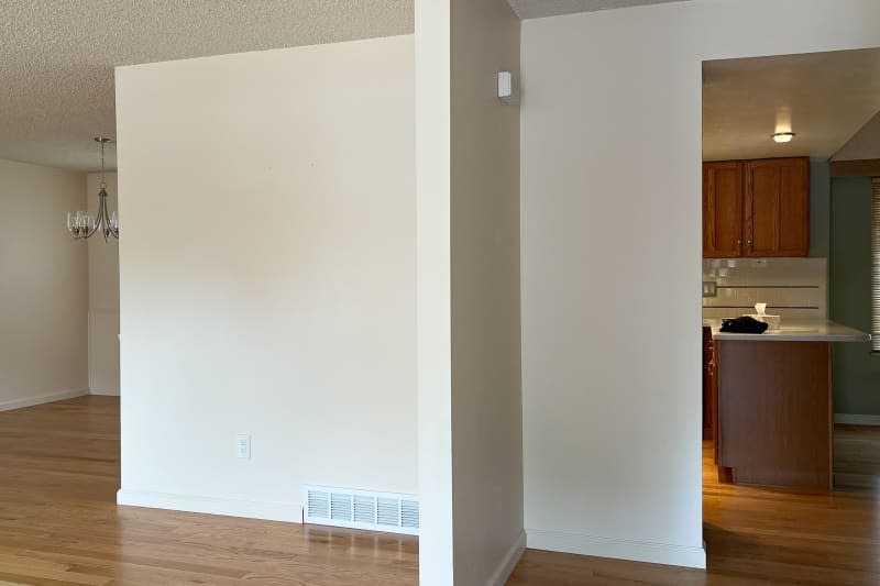 White walls enclosing kitchen with wood cabinets and island.