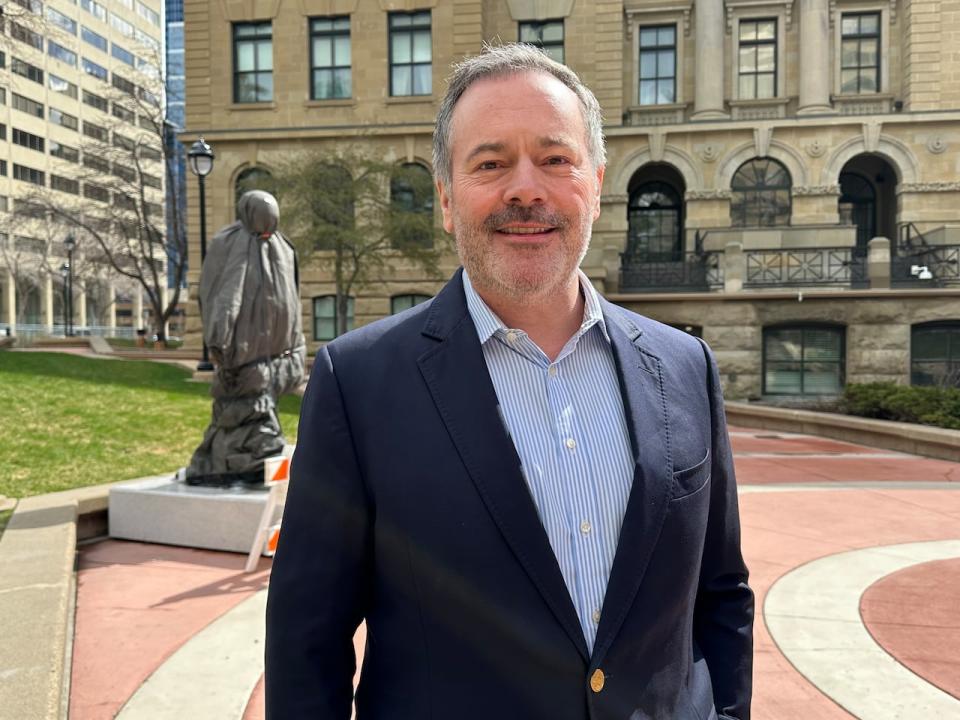 Former Premier Jason Kenney stands near a shrouded statue of Sir Winston Churchill, set to be unveiled on June 6, 2024, in Calgary. Kenney supported the project and announced its location outside the provincial government building.